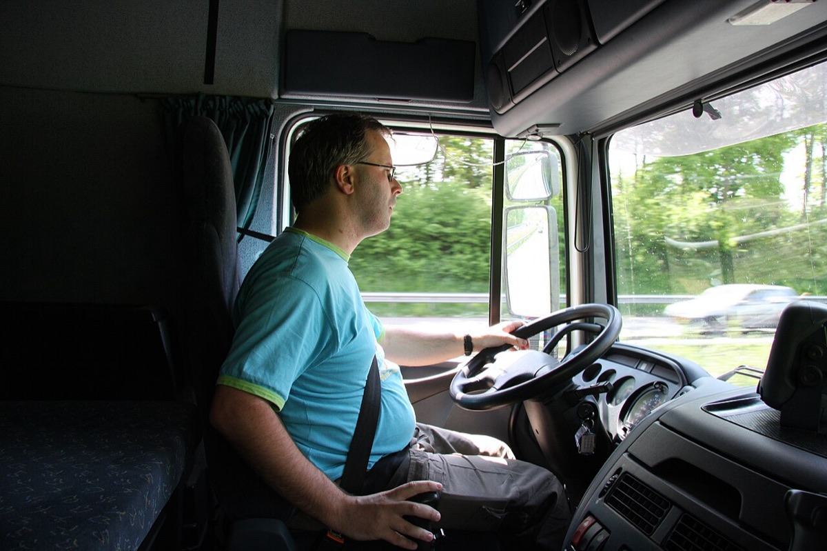 A truck driver at the wheel of a cab on the highway